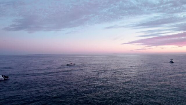 Aerial view of the sea at dawn, sunrise, with boats and pink sky, next to Arcachon