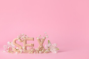 Word SEX with flowers on color background