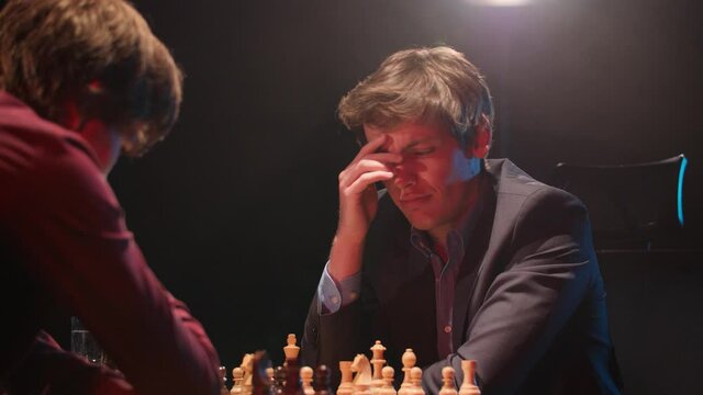 Man in chess match thinks very hard about next move in tournament- low light 