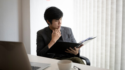 Serious businessman analyzing business information in office.