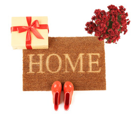 Doormat with gumboots and gift on white background