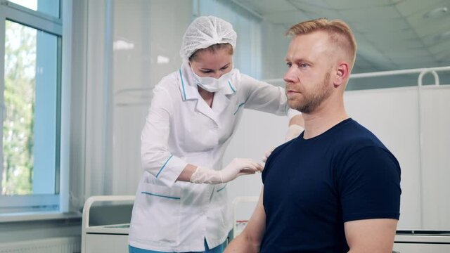 Medical worker is vaccinating a man against covid-19