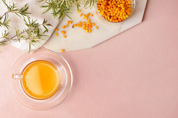 Cup of healthy sea buckthorn tea on color background