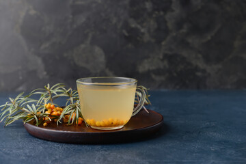Cup of healthy sea buckthorn tea on dark background