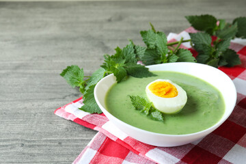 Concept of healthy food with nettle soup on gray textured table