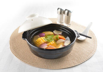 double boiled chinese hot vegetables corn soup in black clay hot pot in white background asian vegan halal menu