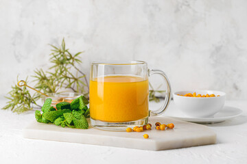 Cup of healthy sea buckthorn tea on light background