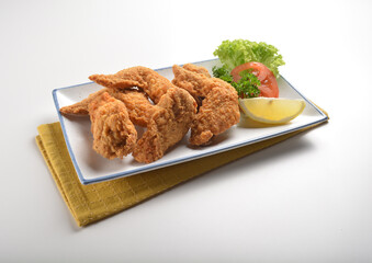 deep fried crispy golden chicken wings with tomato green salad in white background western snack cuisine halal fast food menu