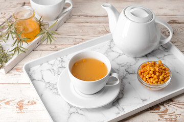 Tray with healthy sea buckthorn tea on table