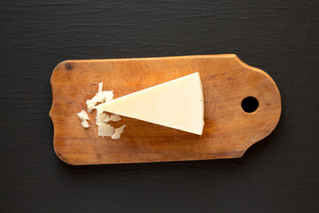 Pecorino Romano Cheese on a rustic wooden board on a black background, top view. Flat lay, overhead, from above.