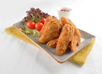 deep fried crispy golden chicken wings with tomato green salad in white background western snack cuisine halal fast food menu