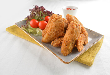 deep fried crispy golden chicken wings with tomato green salad in white background western snack cuisine halal fast food menu
