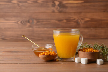 Cup of healthy sea buckthorn tea with honey on table