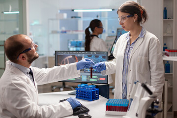 Biochemistry reserarchers doing experiments with blood sample for vaccine development. Medical scientist working with DNA scan image in modern equipped laboratory using high tech technology.