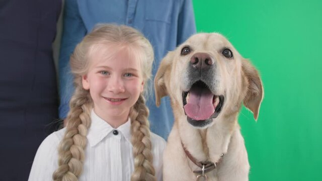 happy childhood, cute little girl with dog and parents, smiling and looking at camera on green background, chroma key
