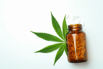 Bottle with pills and cannabis leaf on white background