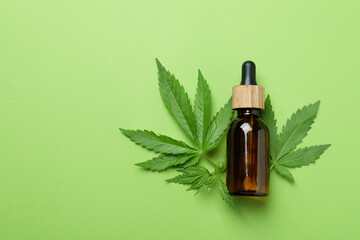 Cannabis oil and leaves on green background