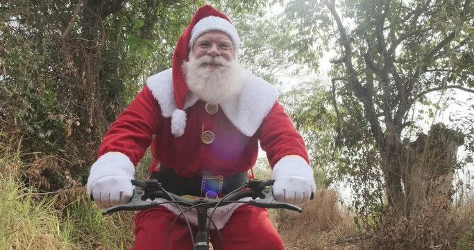 Santa Claus riding a bicycle on dirt road. 4K.