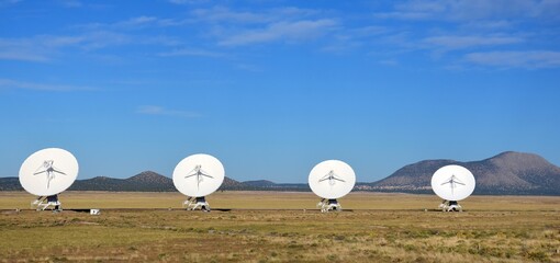 four radio telescopes and giant dish antennas  in the karl g. jansky very large array radio astronomy observatory against a mountain backdrop  near socorro, new mexico