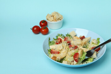 Concept of tasty eating with Caesar salad on blue background
