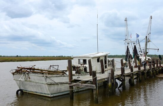 an old fishing boat docked at the wooden pier on the altamaha river in darien , georgia, on a stormy day