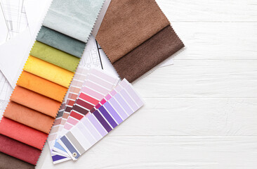 Composition with paint color palettes and fabric samples on white wooden background