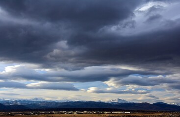 Obraz premium ominous afternoon storm clouds over long's peak and the front range of the colorado rocky mountains, as seen from broomfield, colorado