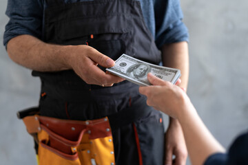 close-up female hand pays for the work of foreman builder repairman with dollar money. construction...