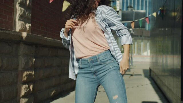 Slow motion of joyful mixed race woman dancing relaxing enjoying music outside in city street. Youth culture and outdoors activities concept.