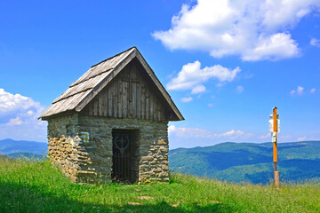 Rural roadside shrine in summer mountain landscape, Beskid Sadecki, Poland