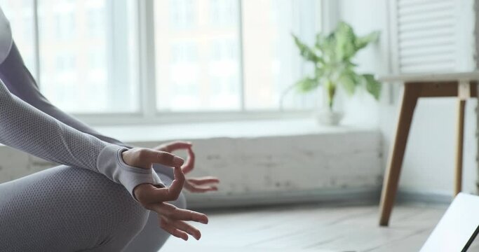 Close up young woman hands meditation and using tablet mobile app for breathing and meditate, happy woman practicing yoga. Female brunette enjoying calm relax harmony Zen mindfulness at home.