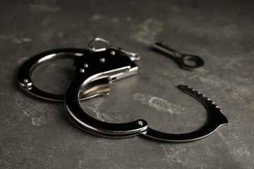 Classic chain handcuffs with key on grey table, closeup