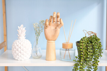 Wooden hand and houseplant on shelf near color wall