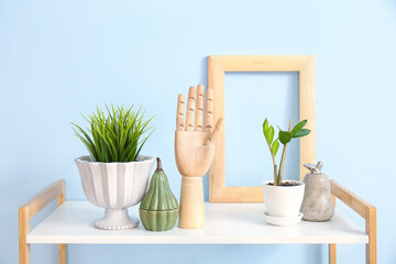 Wooden hand and decor on shelf near color wall