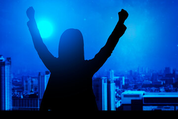 Silhouette of a businesswoman standing and raised hands