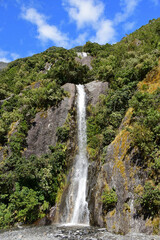 beautiful trident creek waterfalls on a sunny summer  along the franz joseph glacier  walk,  near the town   of franz joseph on the west coast of the south island of new zealand