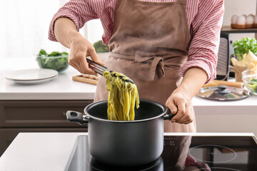 Woman boiling tasty pasta in kitchen