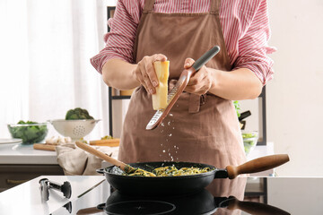 Woman cooking tasty pasta with spinach and cheese in kitchen