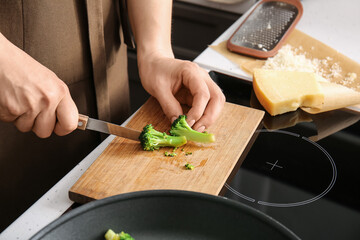 Woman cutting healthy broccoli in kitchen