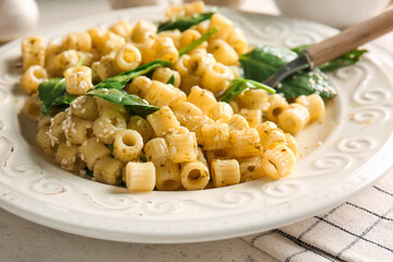 Plate with tasty pasta and spinach on table, closeup