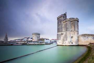 Storm over the entrance of the old harbor of La Rochelle in France, with the Tour de la Chaine on the left side and Tour Saint-Nicolas on the right side, Nouvelle Aquitaine region, France