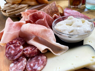 Rustic wooden serving tray with typical products of Italian Emilia-Romagna region: Prosciutto (Ham), Salami, Coppa di testa, ciccioli, sliced and Squacquerone cheese. Brisighella, Ravenna, Italy