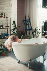 Back view photo of a caucasian woman having spa procedures in a bathtub