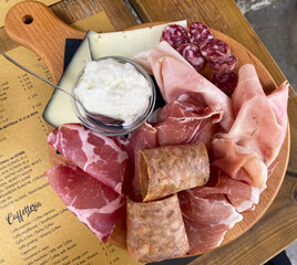 Rustic wooden serving tray with typical products of Italian Emilia-Romagna region: Prosciutto (Ham), Salami, Coppa di testa, ciccioli, sliced and Squacquerone cheese. Brisighella, Ravenna, Italy © Claudio Caridi