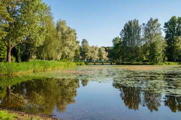 Fototapeta na wymiar View of The Pumpviken park in summer, Mustio river, wooden bridge to the island and trees, Karjaa, Raseborg, Finland