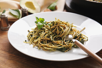 Plate with tasty pasta and spinach on table