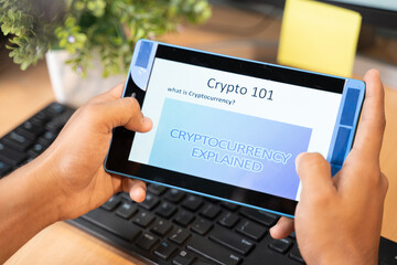 Shoulder shot of unrecognizable man reading or learning about cryptocurrency on tablet.