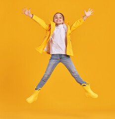 Fototapeta na wymiar Jumping kid in raincoat and gumboots