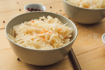 Bowls with tasty sauerkraut on wooden background