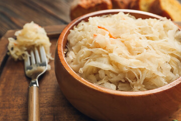 Bowl with tasty sauerkraut on wooden background, closeup